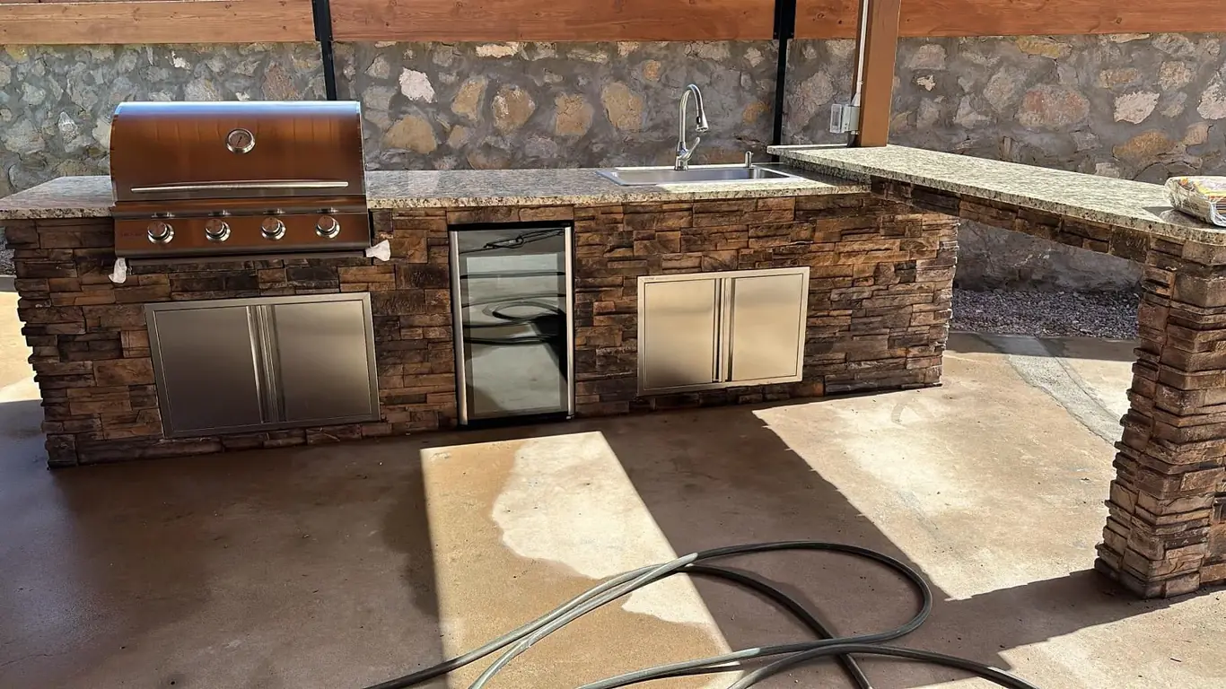 Custom stone outdoor kitchen with grill and beverage fridge